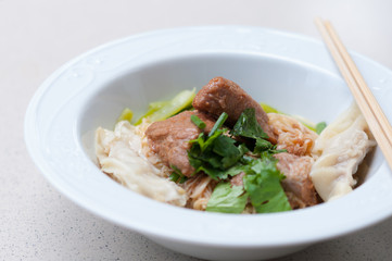 Egg noodle with delicious stewed pork and dumpling in white bowl