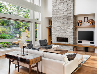 Beautiful living room with hardwood floors and tall fireplace in new luxury home