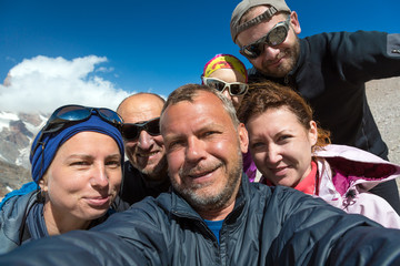 Self Portrait of Group of Merry Climbers Faces of Five People Men and Women Young and Elder Expressing Fun and Joy Blue Sky Background