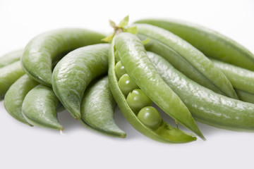 Open pod of peas on a white background close-up.