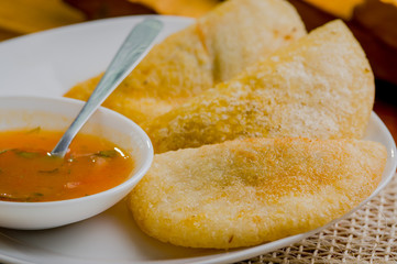 Three empanadas nicely arranged on white platter next to small