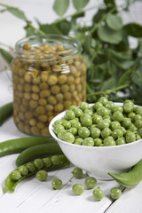 Fresh green peas  and canned peas in a glass jar .