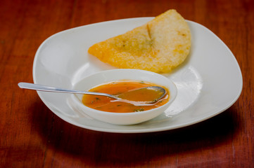 Delicious empanada placed on white plate with small salsa bowl