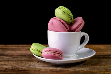macaron piled up inside a coffee cup on wooden table