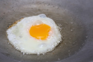 cooking fried egg in hot pan with oil