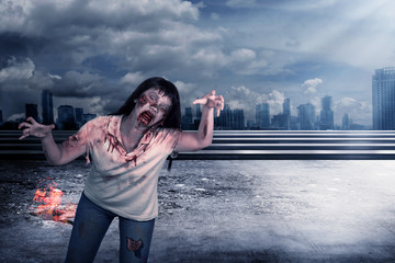 Scary female zombie with burning city background