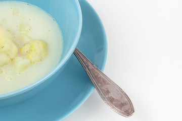 Blue bowl of cauliflower and potatoes soup.