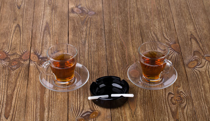 Cups of tea with dishes and cigarettes in ashtray