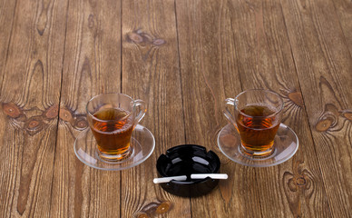 Cups of tea with dishes and cigarettes in ashtray