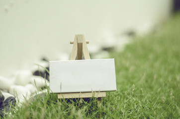 blurred image, white canvas on wooden stand. green grass, bokeh and retro look