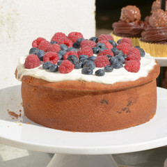 Cake with frosting covered in raspberries and blueberries