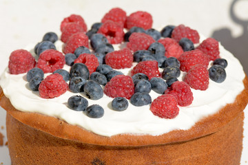 Cake with frosting covered in raspberries and blueberries