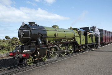 Naklejka premium Maszynista polerujący lokomotywę Green Goddess obsługującą połączenia pasażerskie między Hythe a Dungeness w hrabstwie Kent w Wielkiej Brytanii