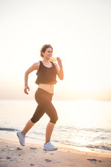 Running woman. Female runner jogging during the sunrise on beach.