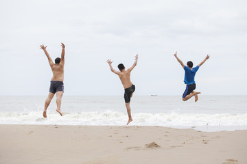 Obraz premium Three men jump on the beach