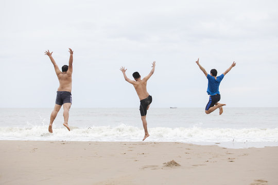 Three Men Jump On The Beach