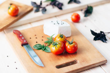 raw food: tomatoes, cheese, basil on kitchen table
