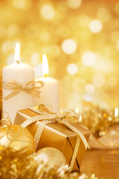 Christmas scene with gold baubles, gift and candles