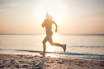Running woman. Female runner jogging during the sunrise on beach.