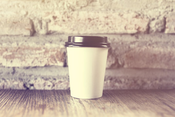 Blank cup of coffee on a brick wall background