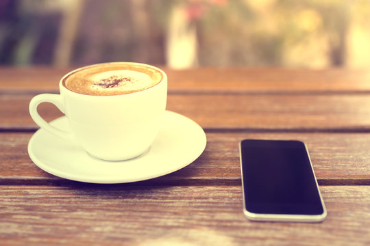 Cell Phone And Cup Of Coffee On A Wooden Table