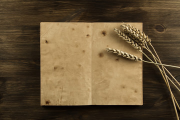 open old vintage book on the aged wooden background. ears of wheat. homemade, menu, recipe, mock up