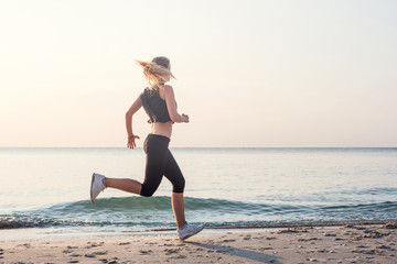 Running woman. Female runner jogging during the sunrise on beach.