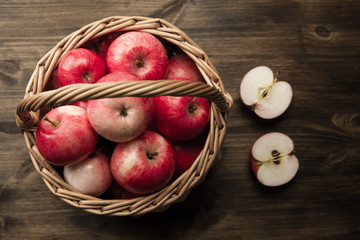 Basket of fresh ripe red apples on wooden background