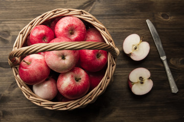Naklejka na ściany i meble Basket of fresh ripe red apples on wooden background
