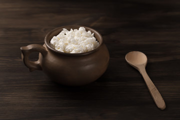 fresh tasty curd in pot on wooden background. Homemade, cottage cheese
