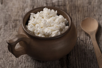 fresh tasty curd in pot on wooden background. Homemade, cottage cheese
