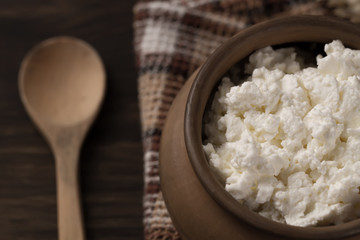fresh tasty curd in pot on wooden background. Homemade, cottage cheese