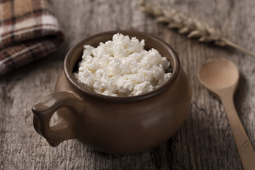 fresh tasty curd in pot on wooden background. Homemade, cottage cheese