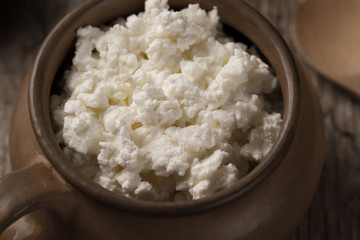 fresh tasty curd in pot on wooden background. Homemade, cottage cheese