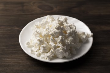 fresh tasty cottage cheese on a plate on wooden background. Homemade, curd