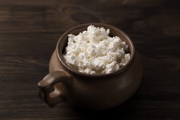 fresh tasty curd in pot on wooden background. Homemade, cottage cheese