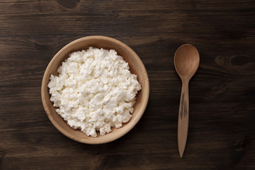 fresh tasty curd in pot on wooden background. Homemade, cottage cheese