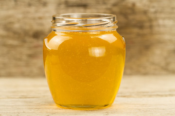 glass jar of fresh honey on wooden background