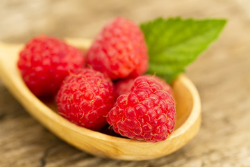ripe raspberry in a spoon with mint leaves closeup on wooden background