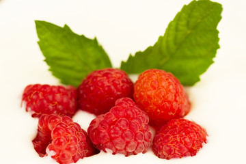 ripe raspberries in cream with mint leaves, macro