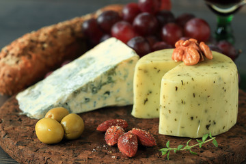 Glass of red wine with various types of cheese, fruits and appetizers