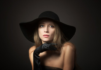 Blond lady in big black hat, studio portrait