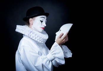 Sad mime Pierrot looking at the mask