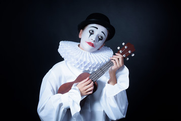 Sad mime Pierrot plays the small guitar - obrazy, fototapety, plakaty