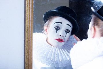 Sad mime Pierrot looking at the mirror