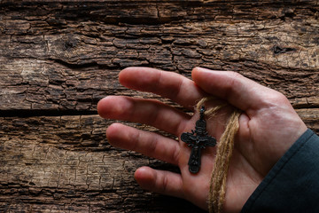 man holding a cross on a wooden background
