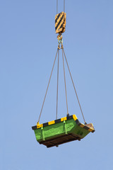 Green builders skip lifted by a crane