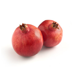 two pomegranates photographed on a white background with a soft
