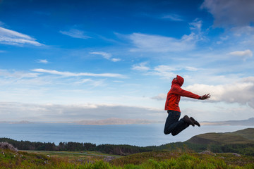 Man jumping on the top pf a mountain, Skye, Scotland - 91330278
