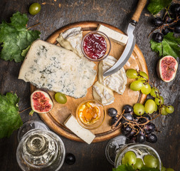 cheese plate with gorgonzola and honey mustard sauce Camembert Jam grapes on a branch wine glasses on a wooden rustic background   top view close up
